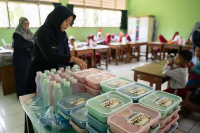 Seorang guru mengatur kotak makan siang yang akan dibagikan selama uji coba program makan siang gratis di sekolah SDN 03 Rorotan di Jakarta, Indonesia pada hari Senin, 30 September 2024. Makanan tersebut merupakan bagian dari program percontohan yang dijalankan pemerintah setelah Presiden Prabowo Subianto menjanjikan makan siang sekolah gratis sebagai bagian dari kampanyenya yang sukses.