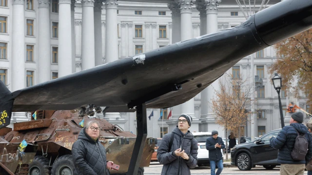 Pessoas observam destroços de um drone russo Geran-2.