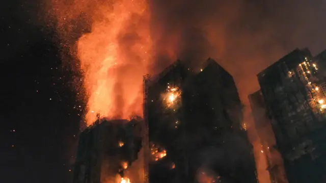 Стовп вогню пронизує будівлі комплексу Wang Fuk Court, язики полумʼя піднімаються високо в небо 