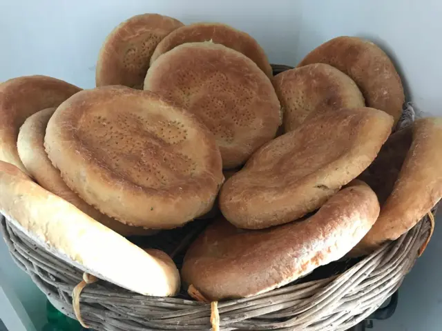 Savat to‘la tandirda yopilgan tansiq non, uning ustiga chapdan quyosh nurlari tushyapti