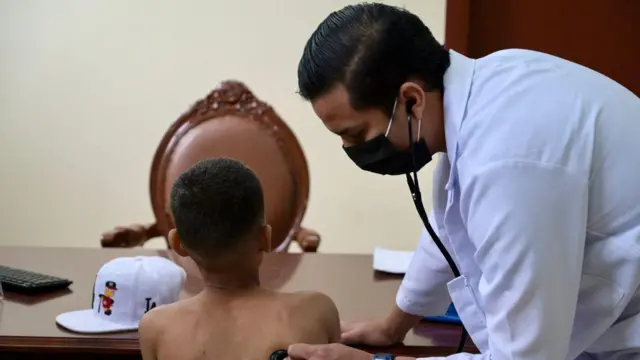 Seorang dokter memeriksa seorang anak yang terkena luka tembak di kantor polisi Ekuador