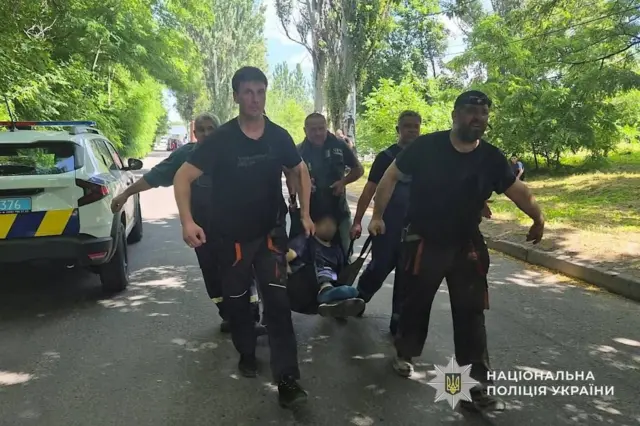 Чоловіки несуть пораненого на ношах