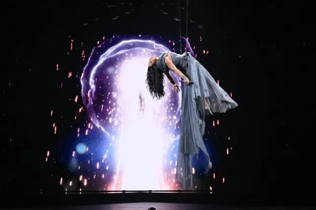 певачица виси с плафона у светлоплавој хаљини