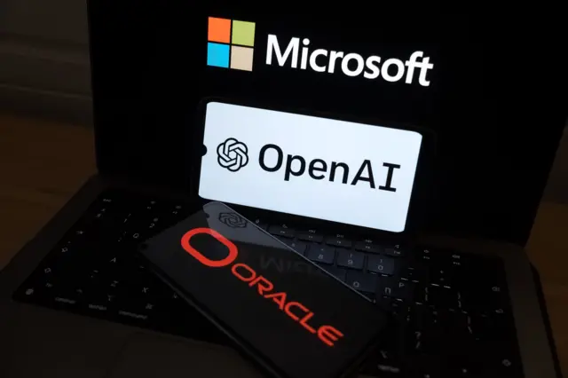 تظهر شعارات «أوبن إيه آي» و«أوراكل» على شاشة هاتف ذكي، بينما يظهر شعار «مايكروسوفت» في الخلفية على شاشة حاسوب محمول، في صورة توضيحية التُقطت في أثينا، اليونان، في 24 مارس/آذار 2026. وبحسب مصادر مطلعة، وافقت «مايكروسوفت» على استئجار مشروع مركز بيانات في ولاية تكساس كان يُطوَّر في الأصل لصالح «أوراكل» و«أوبن إيه آي».