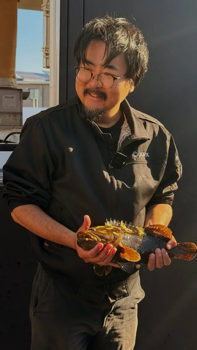 Homem segura peixe nas mãos