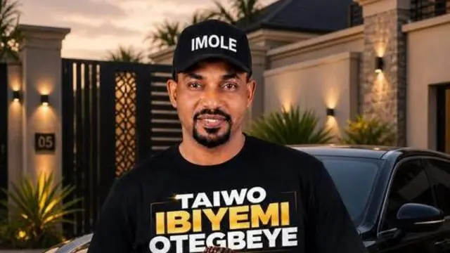 Taiwo Ibiyemi Otegbeye, o wọṣọ dudu o si de fila dudu, o fẹyinti ọkọ, o n rẹrin-in
