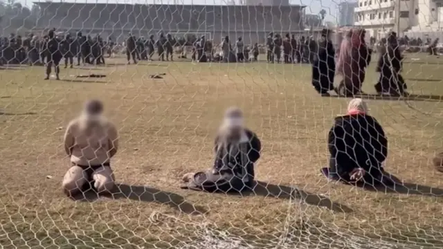 چند مرد و زن با چشمان بسته پشت دروازه فوتبال استادیومی در غزه زانو زده‌اند