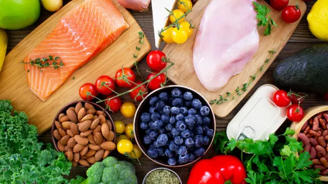 Продукти для здорового харчування, зокрема свіжий лосось, куряча грудка, боби, горіхи та яйця, а також велика кількість фруктів і овочів, багатих на антиоксиданти