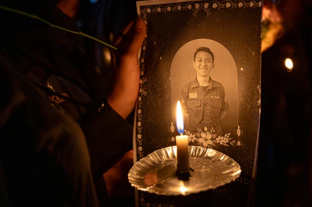 Seorang peserta menyalakan lilin dan membawa foto Iko saat aksi solidaritas meninggalnya mahasiswa Fakultas Hukum Universitas Negeri Semarang (Unnes) Iko Juliant Junior di Unnes, Semarang, Jawa Tengah, Selasa (02/09).