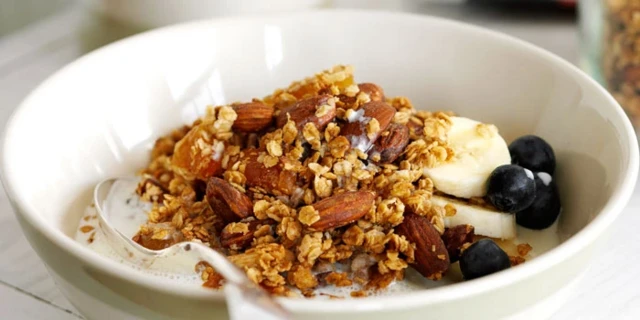 Bol avec un mélange de céréales, de noix, de fruits et de lait