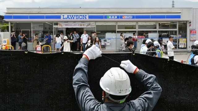 많은 사람이 몰린 일본 로손 편의점 앞에 가림막을 설치하는 인부의 뒷모습