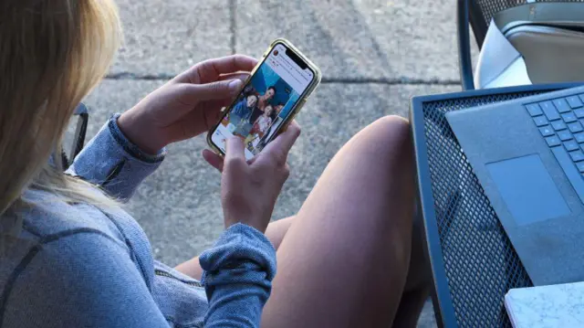 Una mujer con un celular en su mano. 