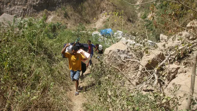 Sejumlah warga membawa bantuan menyusuri jalanan berbatu dari posko bantuan Desa Rokirole ke Desa Nitunglea, Pulau Palue, Kabupaten Sikka, NTT, Rabu (19/8/2026).