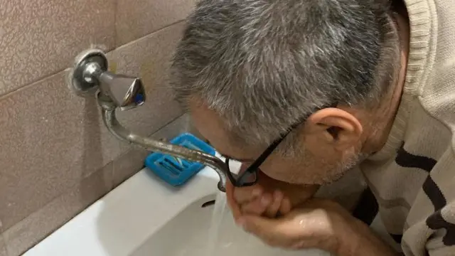 Muškarac pije vodu sa česme