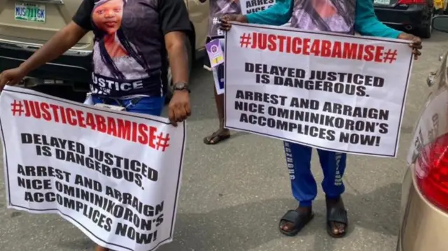 A banner dey held by one woman and anoda man hold banner for her back.