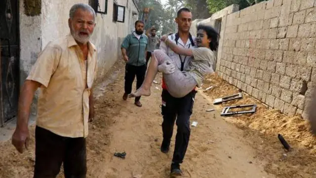 Ahitwa Khan Younis muri Gaza umugabo atwaye umwana w'umunyepalestina wakomeretse nyuma y'igisasu cya Israel  