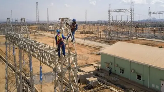 विद्युत प्रसारण लाइन बनाउँदै दुईजना कामदारहरू