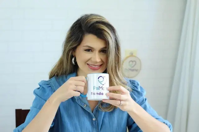 Nanda Perim aparece na foto segurando uma caneca com a logo do seu consultório