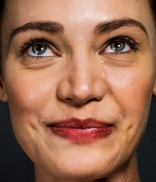 한 여성이 눈물을 흘리면서도 입은 웃고 있다 