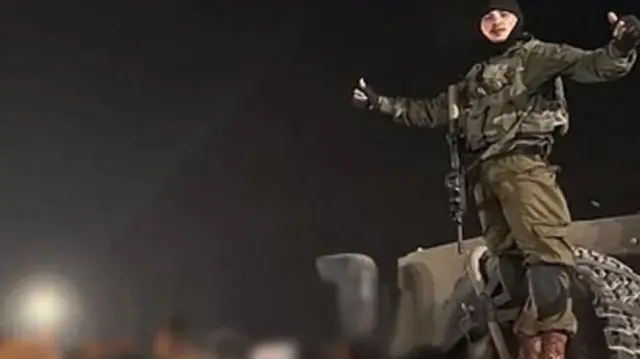 جندي إسرائيلي يقف على شاحنة صغيرة مع معتقلين معصوبي الأعين