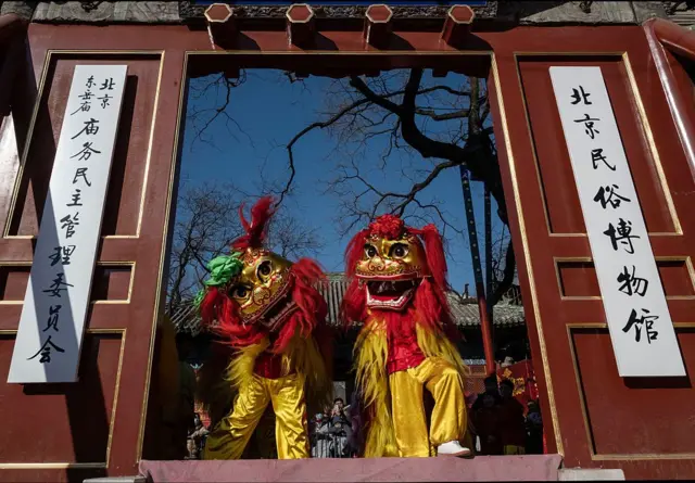 Два человека в костюме львов входят в ворота