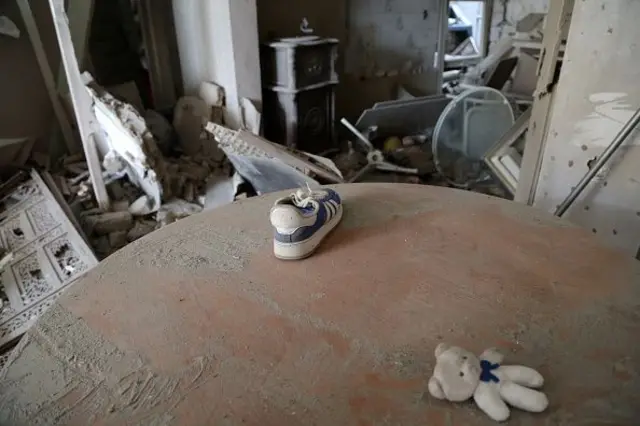 इराणच्या पूर्व तेहरानमध्ये इस्रायल आणि अमेरिकेच्या हल्ल्यांनंतर रिसालत स्क्वेअरजवळील नष्ट झालेल्या इमारतीमध्ये एका घरातील टेबलावर शूज आणि एक टेडी बेअर दिसत आहे. या घरात राहणाऱ्या चिमुकल्याचा हा टेडी असावा.