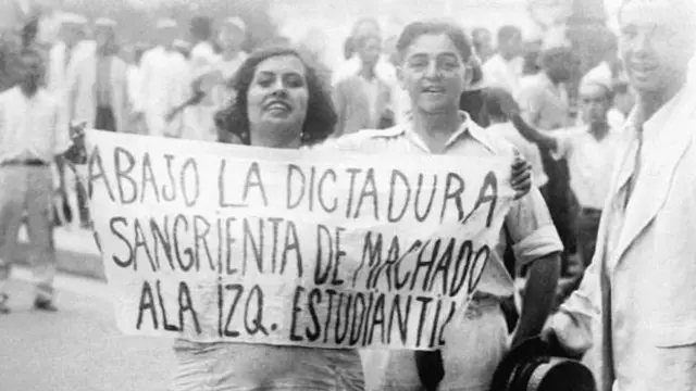 Estudantes protestando contra a repressão em Cuba sob o regime de Machado, com cartaz em que se lê: 'Abaixo a ditadura sangrenta de Machado'