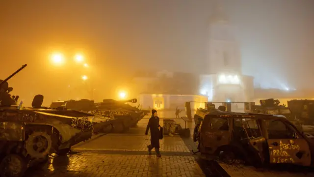 Kiev'deki Aziz Michael Altın Kubbeli Manastırı önünde hasar görmüş araçların arasında yürüyen bir kadın (24 Aralık 2024)