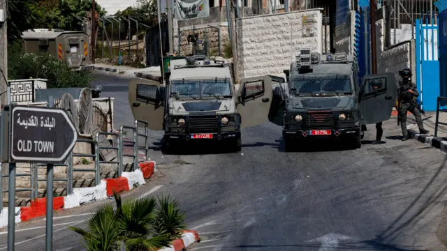 يقف أفراد من القوات الإسرائيلية بالقرب من مركبات عسكرية أثناء مداهمة إسرائيلية في رام الله، في الضفة الغربية المحتلة.