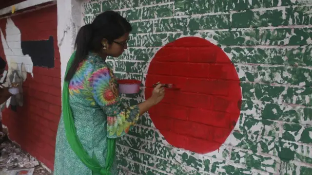 ఢాకాలో ఒక గోడపై 2024 ఆగస్టు 12న పెయింట్ చేస్తున్న ఒక యువతి