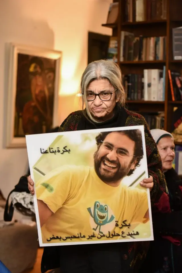 ليلى سويف تحمل صورة ابنها علاء عبد الفتاح في يناير/كانون الثاني 2025 في القاهرة بعد 100 يوم من إضرابها قبل عودتها إلى لندن