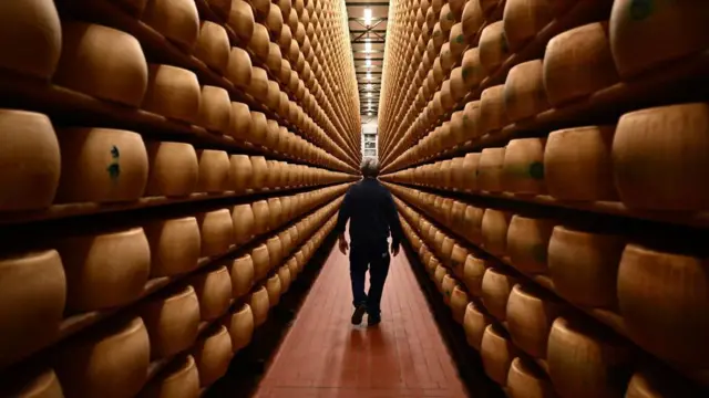 Un trabajador camina junto a ruedas de queso Parmigiano Reggiano almacenadas en el departamento de maduración de la Casearia Castelli, miembro del Grupo Lactalis, en el Caseificio Tricolore en Reggio Emilia, norte de Italia.