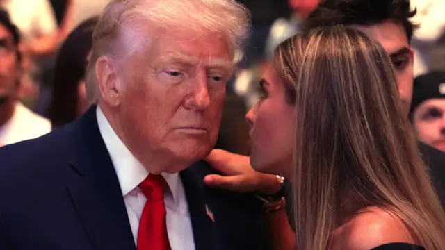 特朗普(左)在佛罗里达迈亚密出席终极格斗冠军赛(UFC),嫡长孙女凯伊·特朗普(Kai Trump;右)与他交头接耳(11/4/2026)