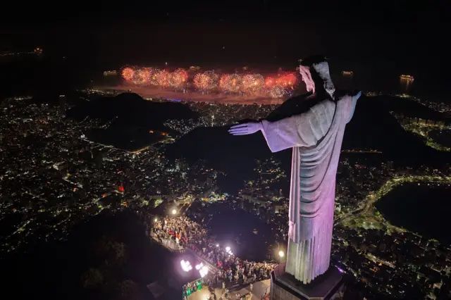 Una vista aérea de la estatua de Cristo Redentor y la panorámica de la playa de Copacabana iluminada con fuegos artificiales