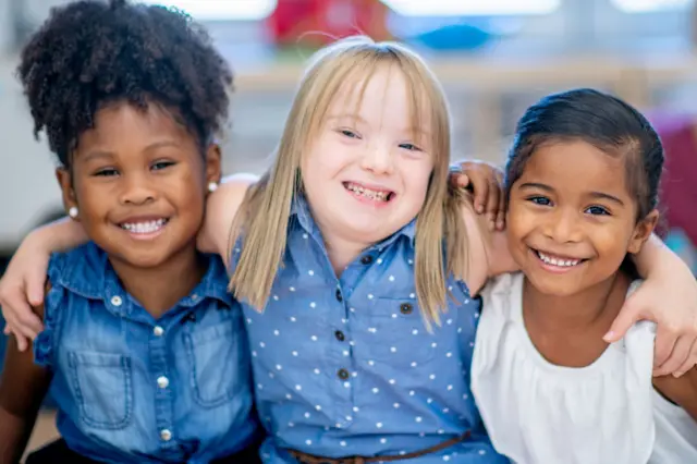 Abana bo mw'ishure ry'incuke bafatanye begeranye, umwe wo hagati afise DS