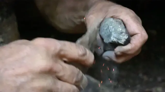 Duas mãos fazendo fogo com uma pedra