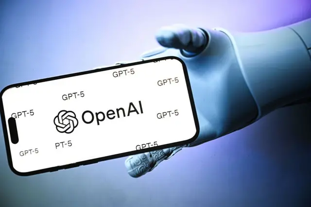 شعار OpenAI على شاشة الهاتف المحمول يحملها روبوت