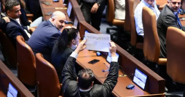 Bir milletvekili elindeki kağıdı kaldırmış, arkadan görüyoruz
