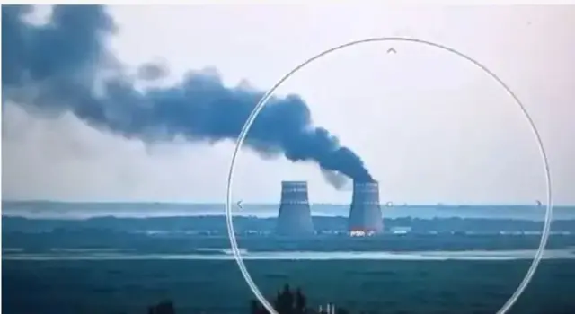 Вигляд здалеку на ЗАЕС, на якій вирує пожежа. Видно величезний стовп диму.