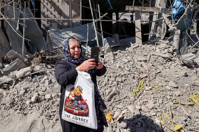 एक महिला तिच्या फोनने फोटो काढत आहे. 