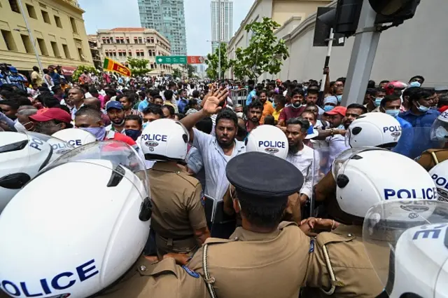 Government supporters and police confront each other outside the President's office in Colombo on May 9, 2022. - Violence raged across Sri Lanka late into the night on May 9, 2022, with five people dead and some 180 injured as prime minister Mahinda Rajapaksa quit after weeks of protests. (