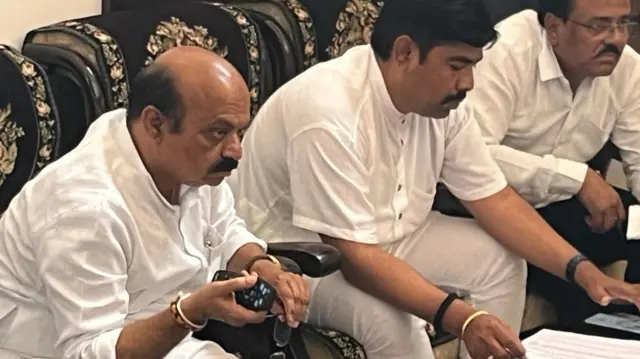 বিদায়ী মুখ্যমন্ত্রী বাসবরাজ বোম্মাই (বাঁদিকে) দলের দপ্তরে টিভিতে নির্বাচনী ফলাফলে খবর দেখছেন