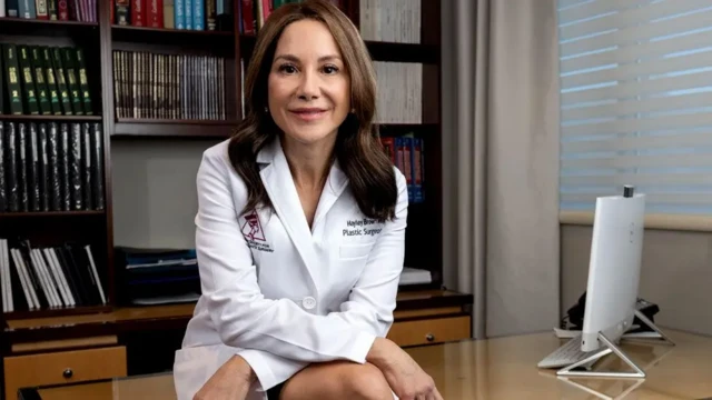 هایلی براون نشسته و یک دستش روی دست دیگر است به دوربین نگاه می‌کند و لبخند می‌زند