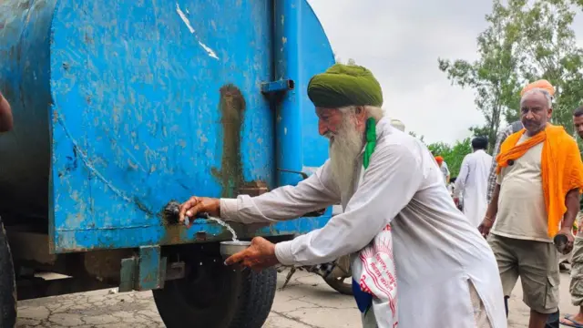ਬਜ਼ੁਰਗ ਕਿਸਾਨ ਭਾਂਡੇ ਵਿੱਚ ਟੈਂਕਰ ਤੋਂ ਪਾਣੀ ਭਰਦੇ ਹੋਏ