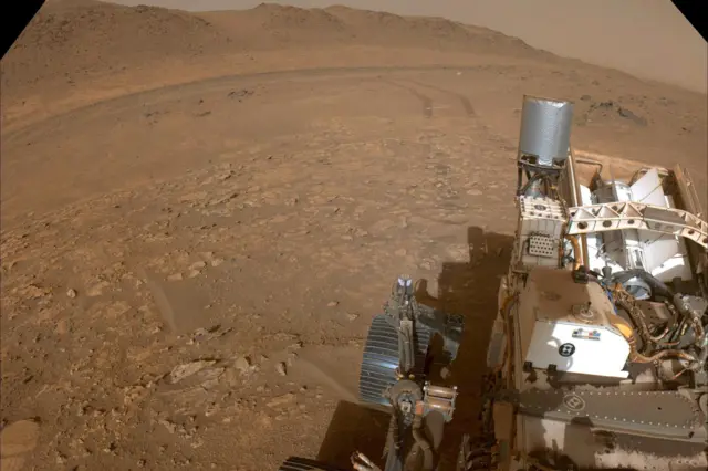 Mars yüzeyinde çekilmiş bir görüntü. Ön planda büyük Perseverance Rover görülüyor; arka planda ise Mars’taki Bright Angel Formasyonu var.