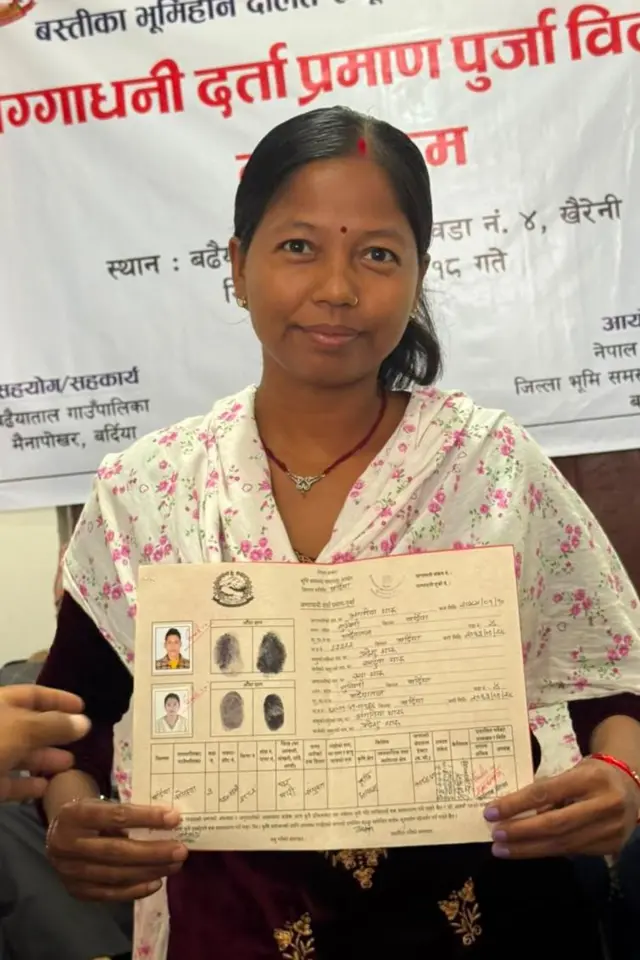 लालपुर्जा देखाउँदै फोटो खिचाइरहेकी महिला
