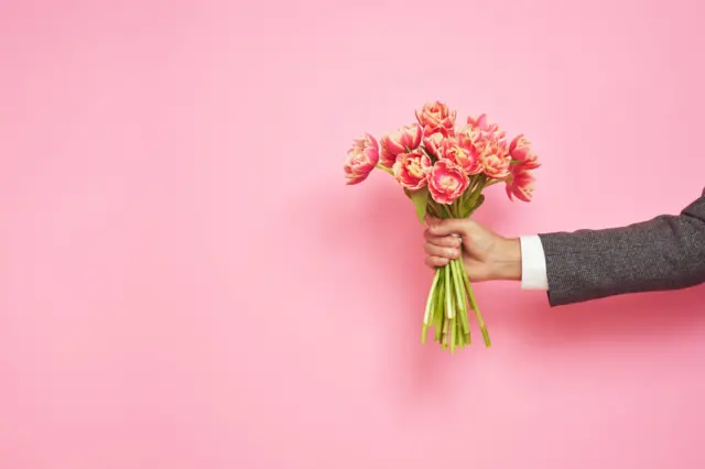 Mão de homem segurando buquê de flores