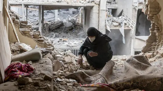 Una mujer remueve los escombros de su casa tras los ataques con misiles, el 15 de marzo de 2026, en Teherán, Irán.