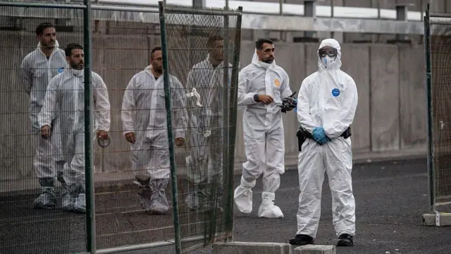 Trabajadores llegan con ropa de protección tras el atraque del MV Hondius en el puerto de Granadilla el 10 de mayo de 2026 en Tenerife