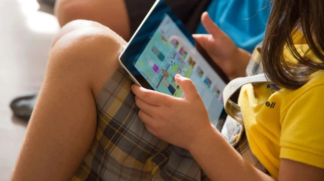 یک کودک که چهره او پیدا نیست، آیپدی در دست دارد